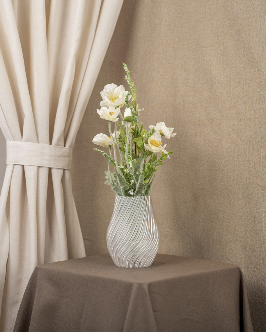 Vintervad Design Ida vase in clear, eco-friendly material with spiral details, holding a bouquet of white flowers.