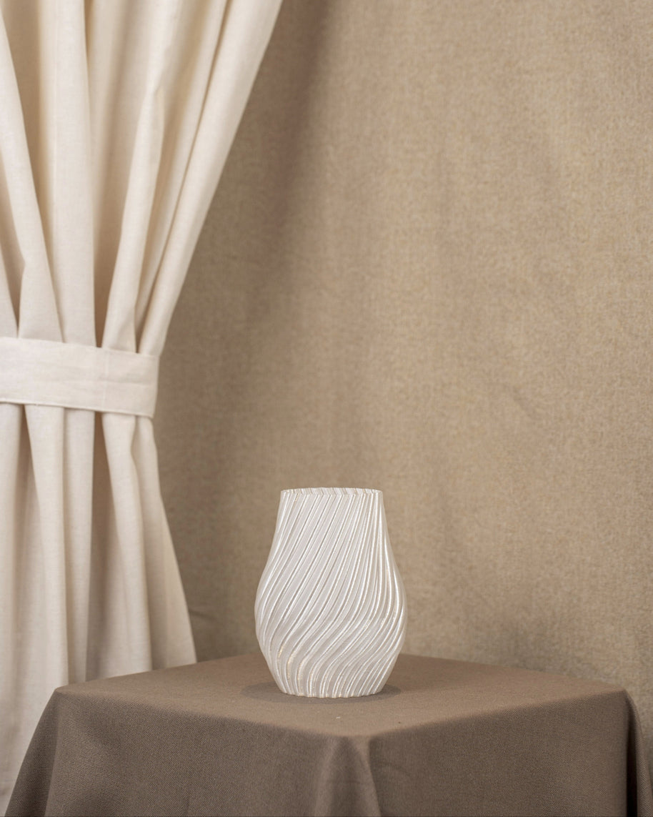 Vintervad Design Ida vase in clear, biodegradable material with elegant spiral patterns on a brown table.