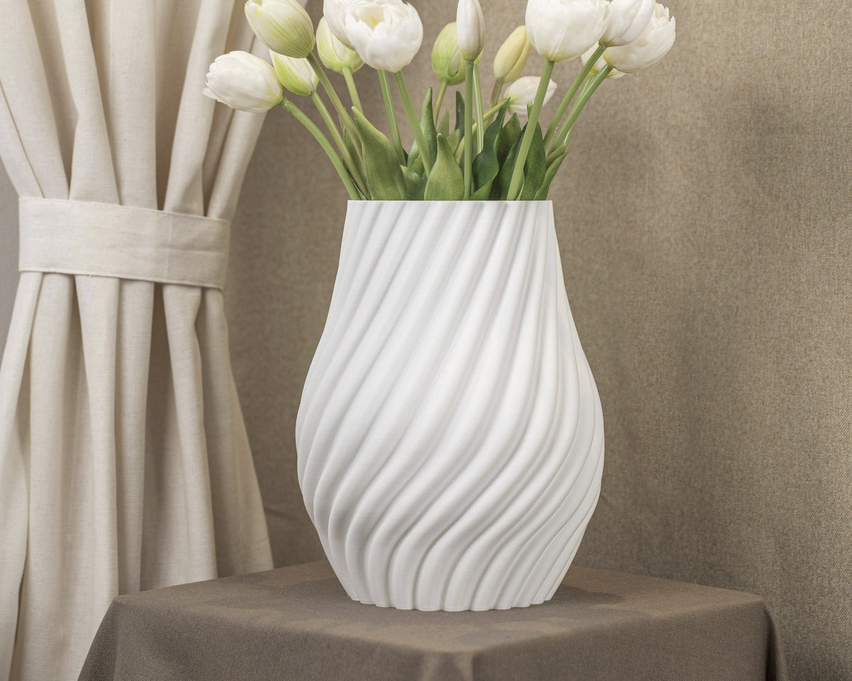 Vintervad Design Ida vase in white with a modern spiral design, holding a bouquet of white tulips on a table.