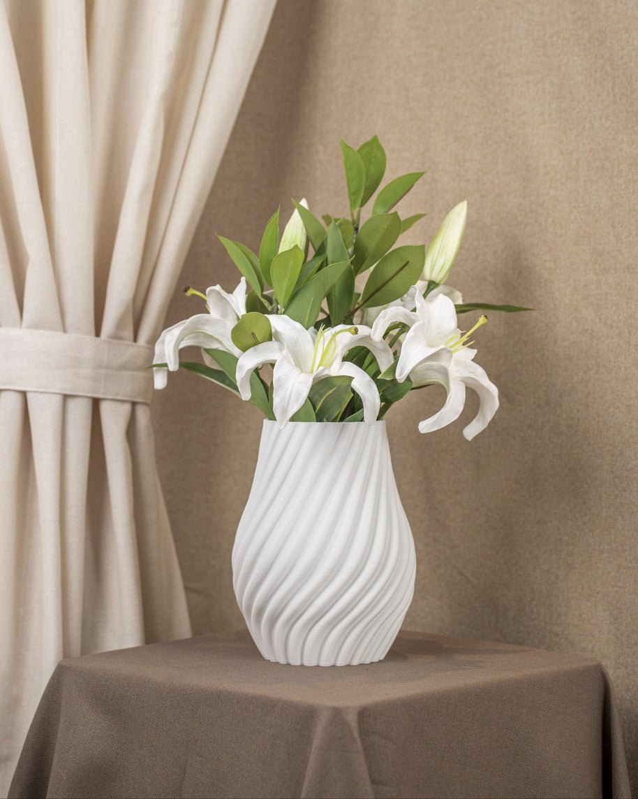 Vintervad Design Ida vase in white with a spiral textured surface, holding a bouquet of white lilies on a table.