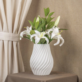 Vintervad Design Ida vase in white with a spiral textured surface, holding a bouquet of white lilies on a table.